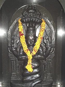 A carved image of Sage Patanjali, crowned by a many-headed cobra and garlanded with marigolds
